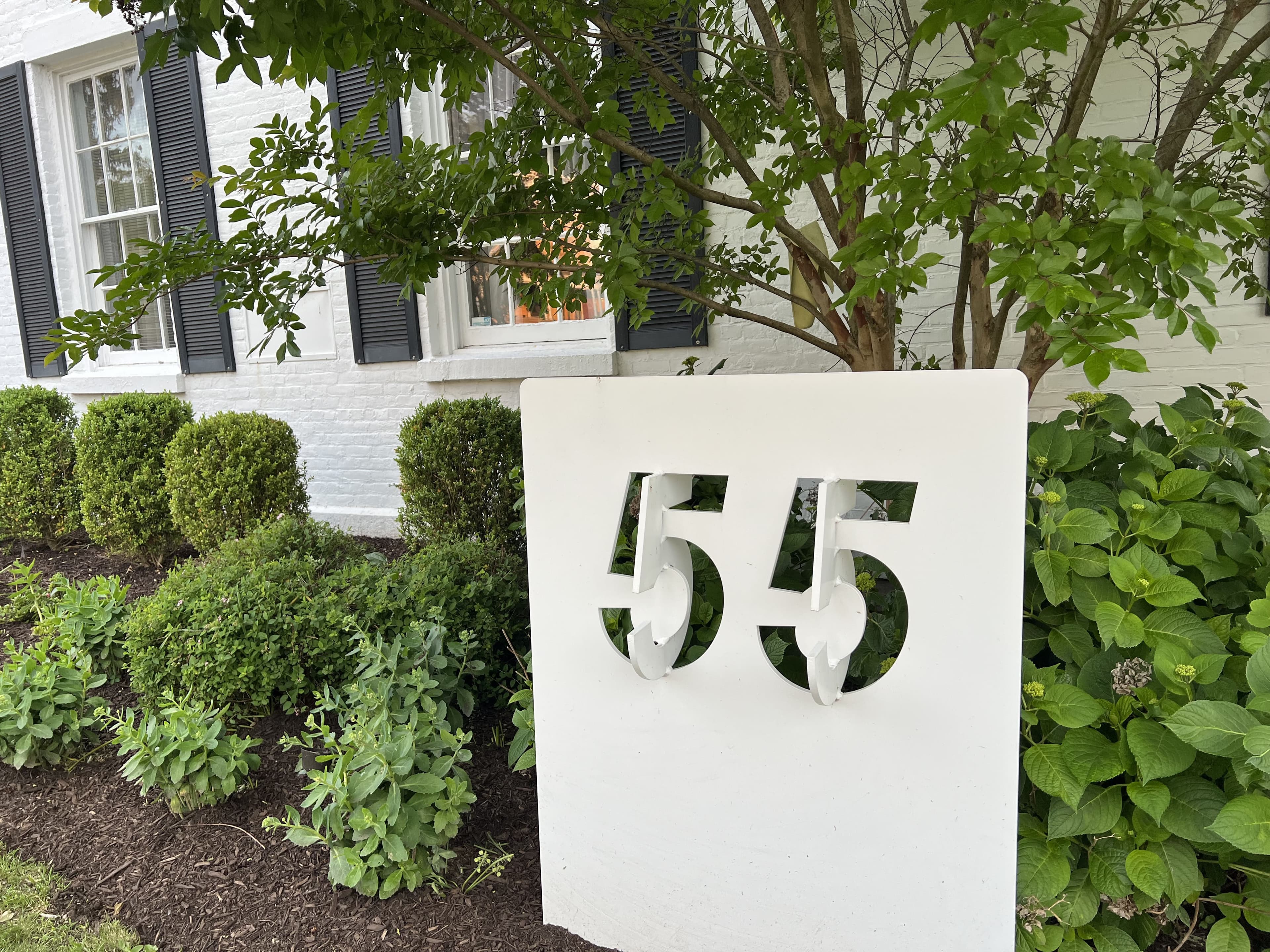 The number 55 sign among the shrubs