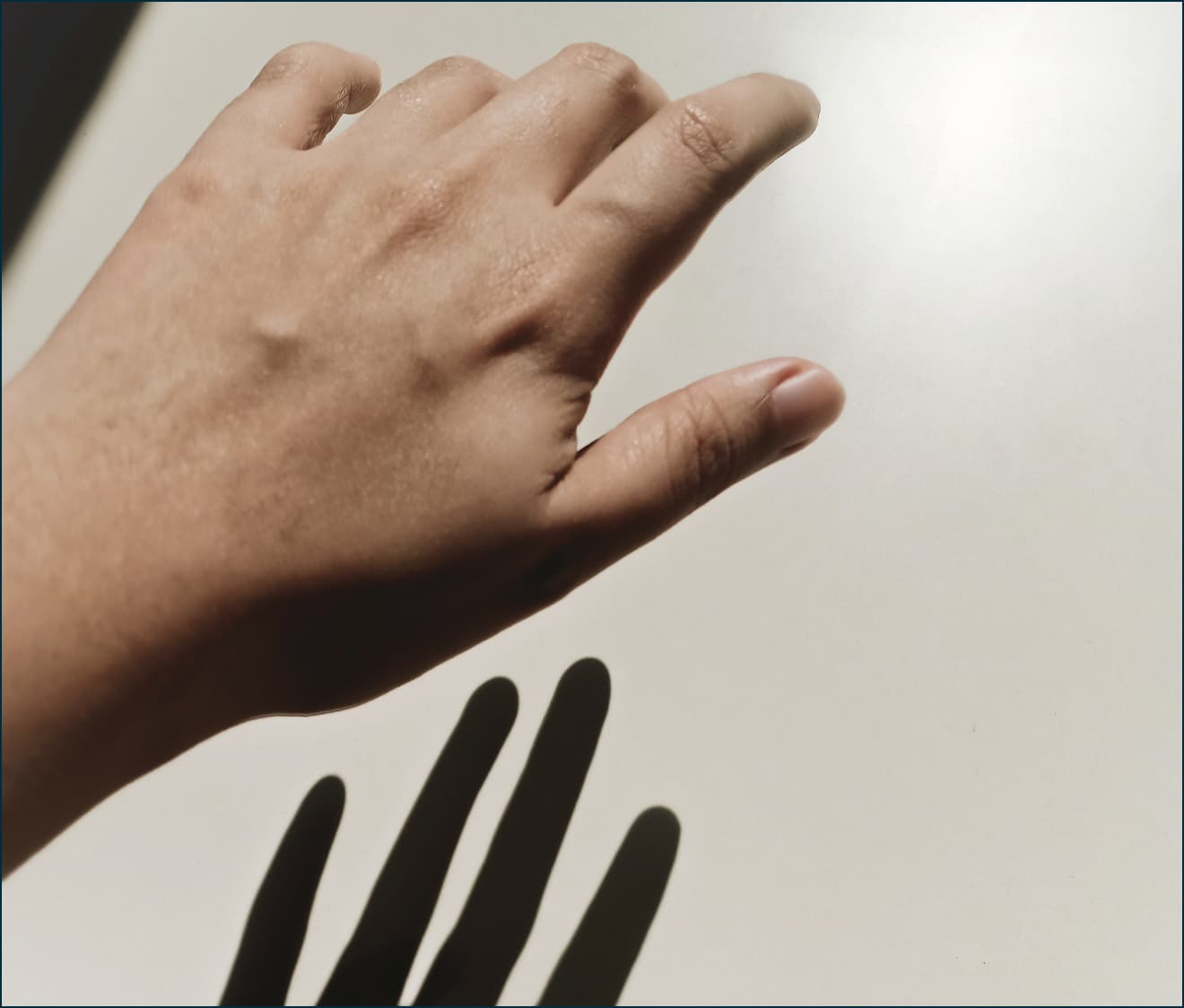 Hand casting a shadow on a pale wall